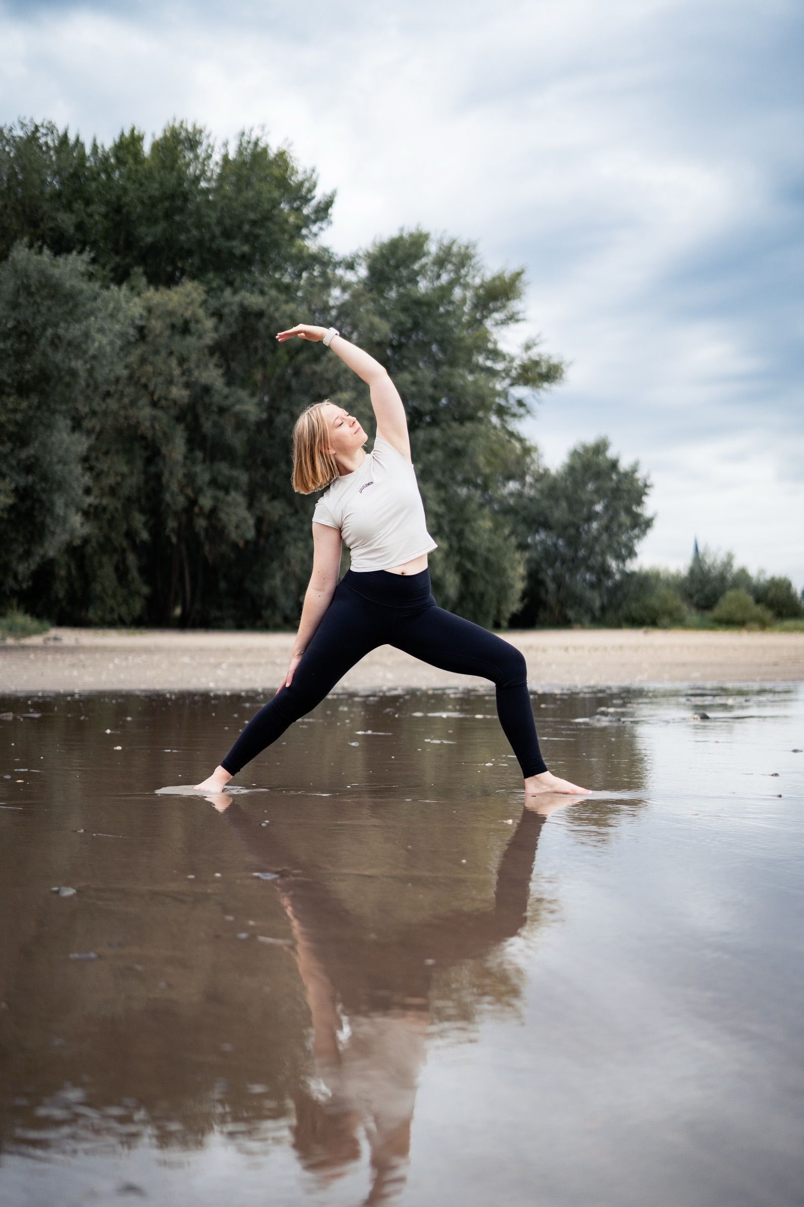 Ein Bild von Julia, die in der Natur steht und den friedlichen Krieger praktiziert.
